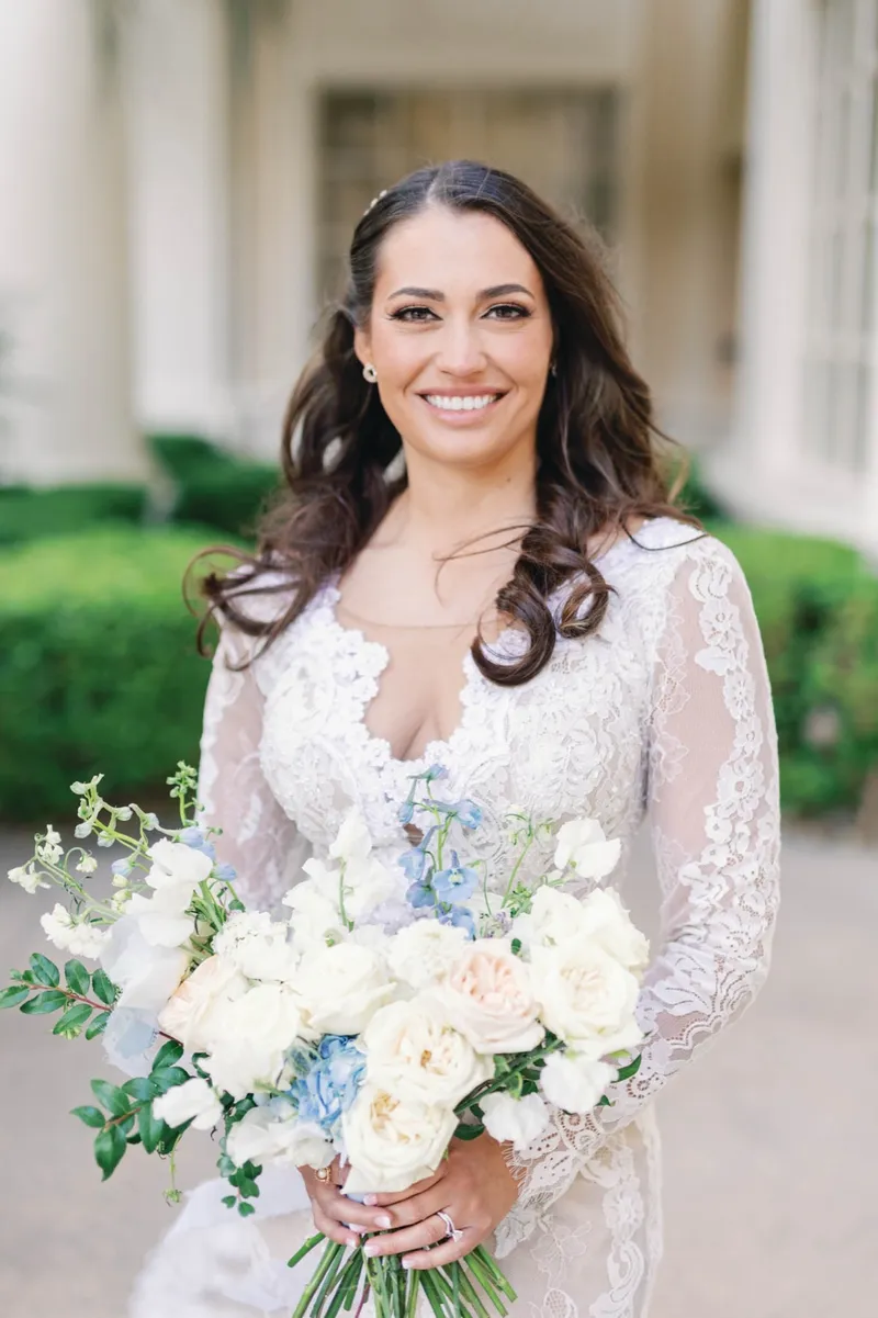 Bridal portrait in a long sleeve lace gown with her veil trailing on the pavement behind her