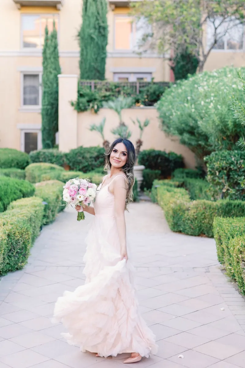 Bride walking the garden path with the ruffled skirt of her gown swinging out to one side
