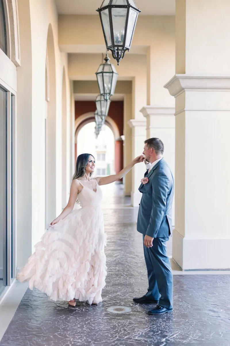 Bride reaching for the groom in a covered walkway with iron lanterns hanging overhead