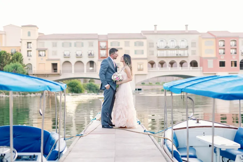 Couple nose to nose on the dock with the moored boats on one side and the village behind