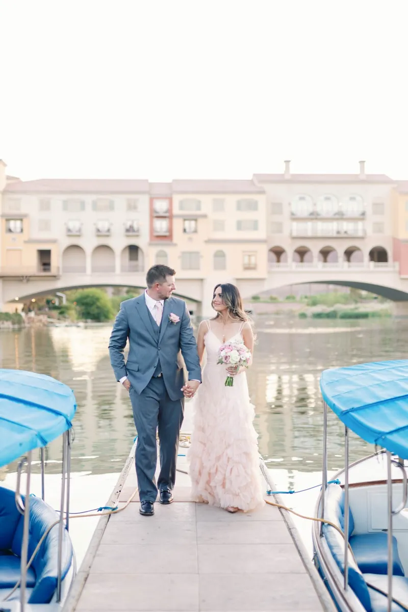 Bride and groom walking the dock hand in hand past the tied up boats