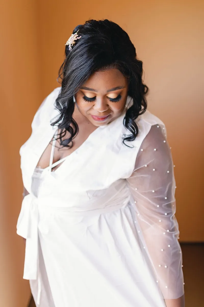 Bride looking down and smiling in warm indoor light with her hair pinned back