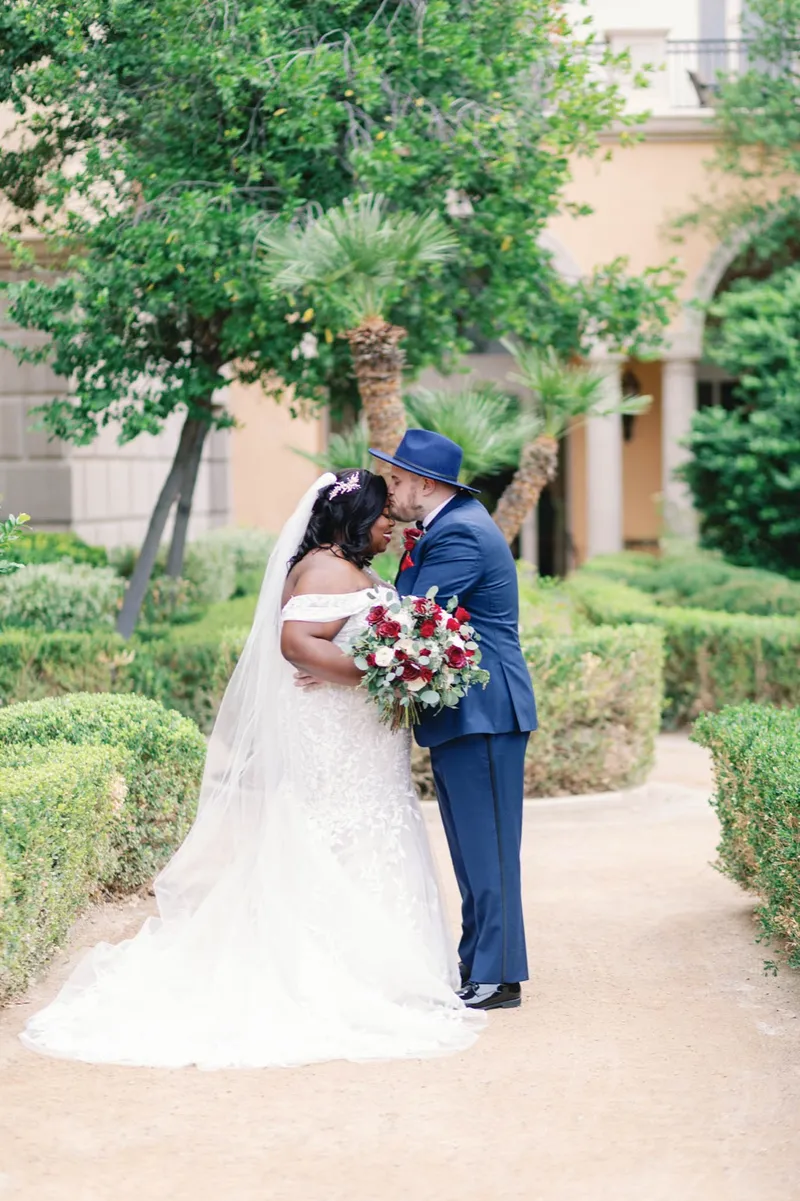 Couple embracing on the garden path with the bride's cathedral veil laid out behind her