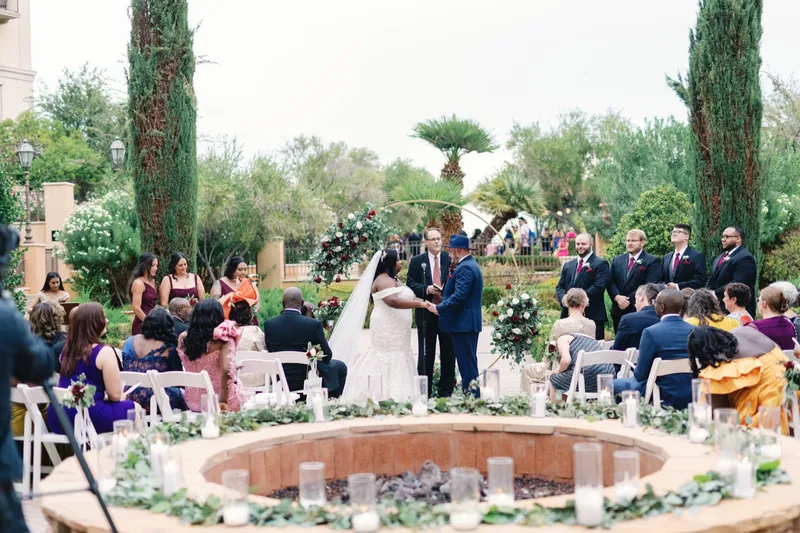 Wide view of the ceremony with candles set all around the low stone rim of the fire feature