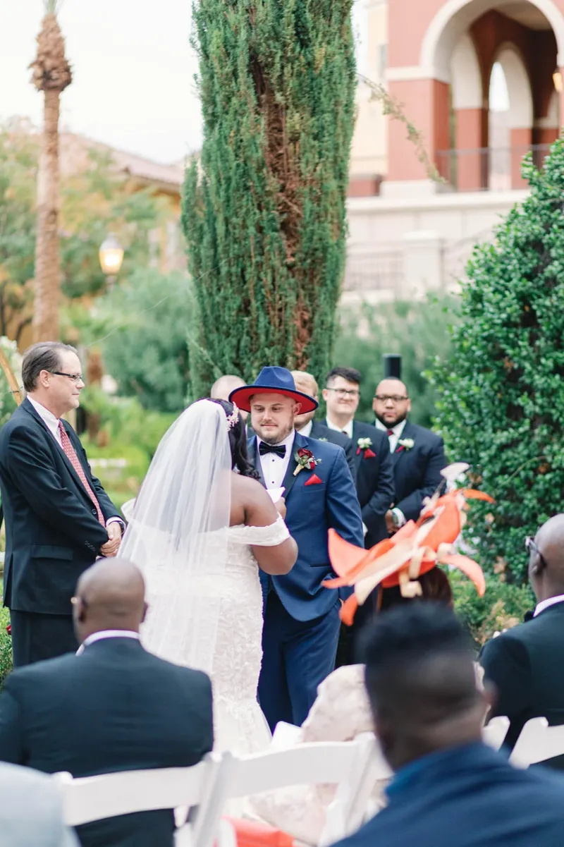Guests fanning themselves with orange paper fans as the couple stand at the front