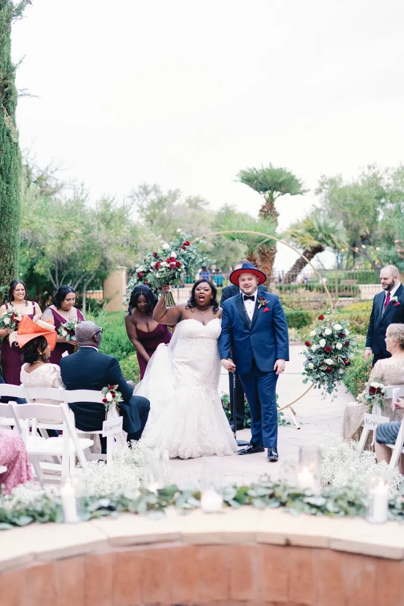 Newly married couple with their arms up in celebration in front of their guests