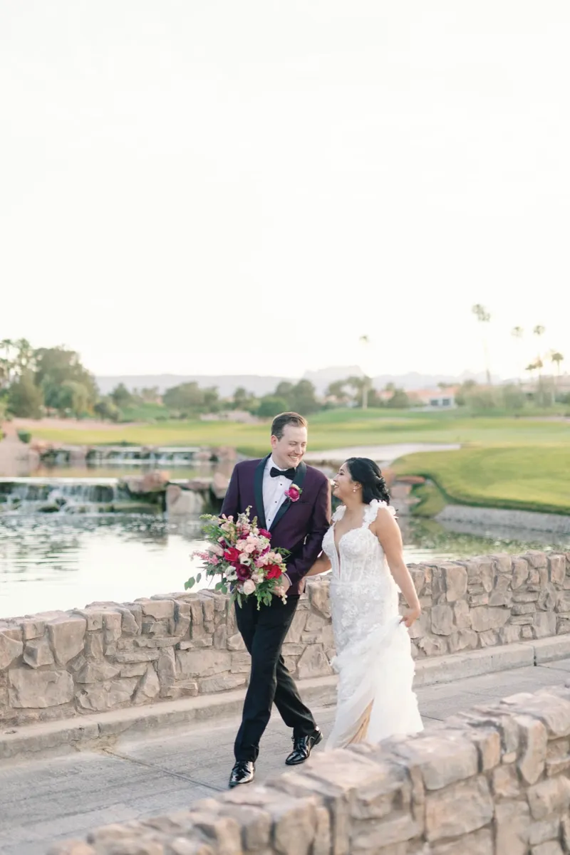 Couple standing together on the stone bridge over the water, the bride laughing