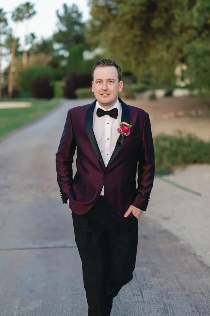 Groom walking up the cart path toward the camera with one hand in his pocket