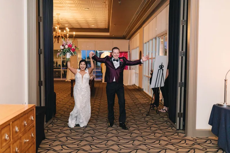 Bride and groom throwing their arms up as they come through the open ballroom doors for their entrance