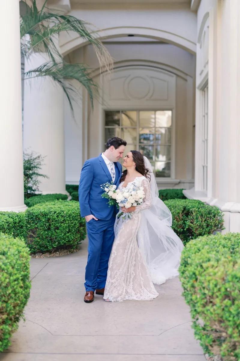 Bride and groom laughing together as they walk past the boxwood hedges