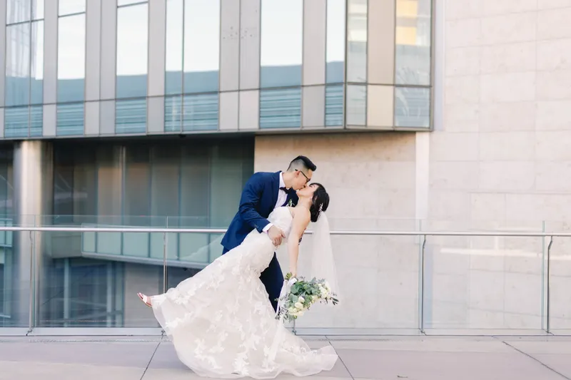 Groom dipping the bride into a kiss in front of the glass facade