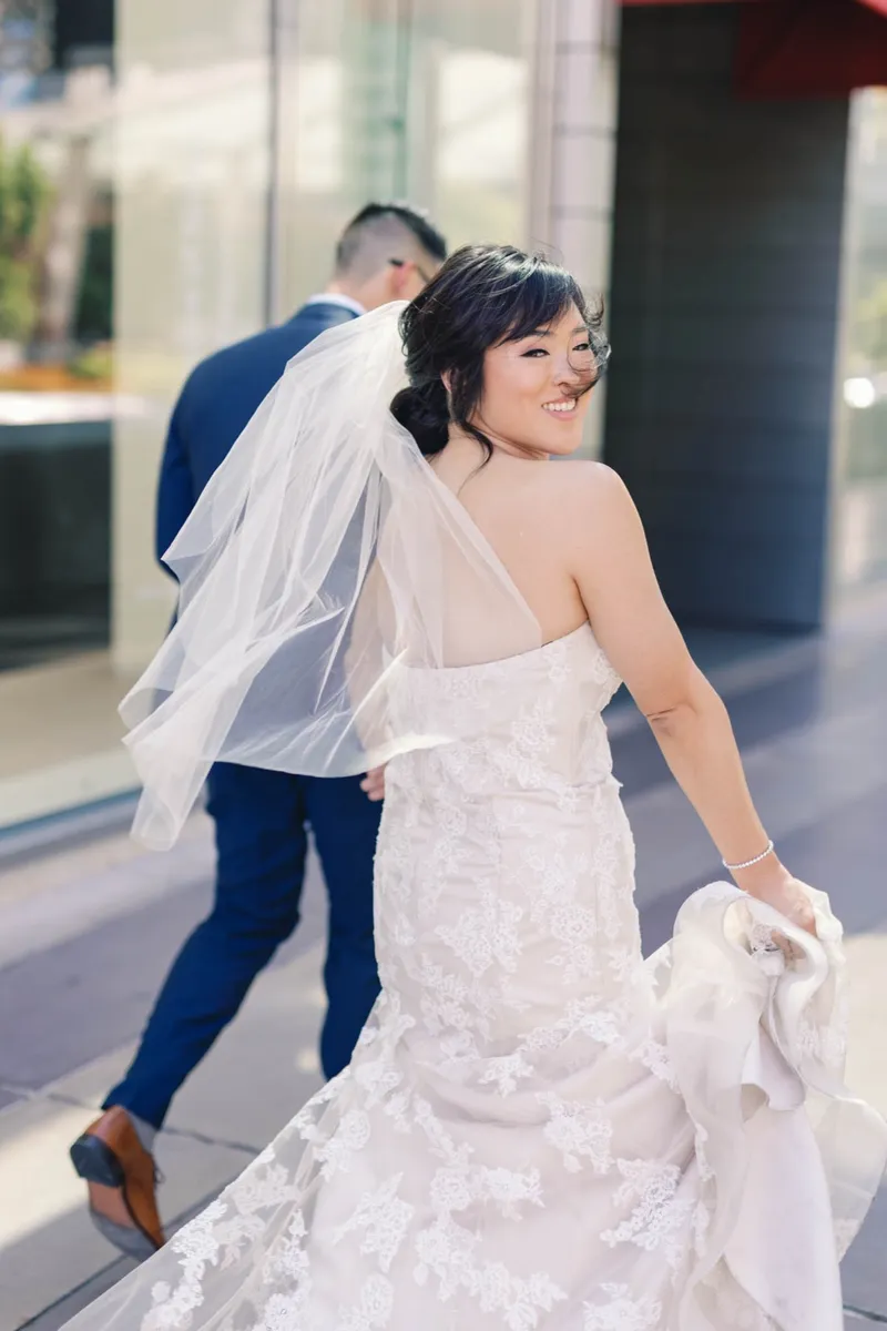 Bride walking ahead with her veil floating out behind her and the groom close at her side