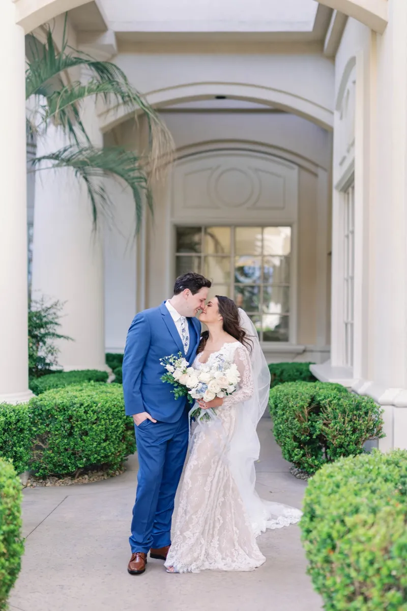 Bride and groom leaning in to kiss on the shaded garden walkway