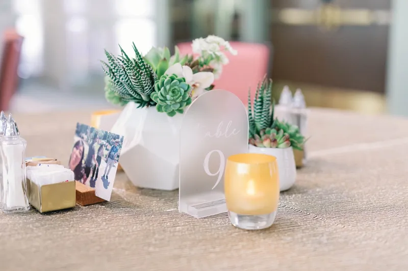 Table nine marker with succulents, a lit candle and a framed photo beside it