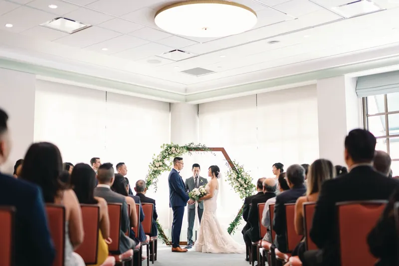 Ceremony seen from the back of the room over rows of seated guests
