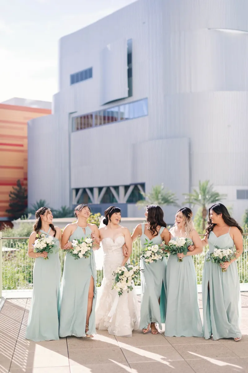 Bride and her bridesmaids in sage green walking together on the outdoor terrace