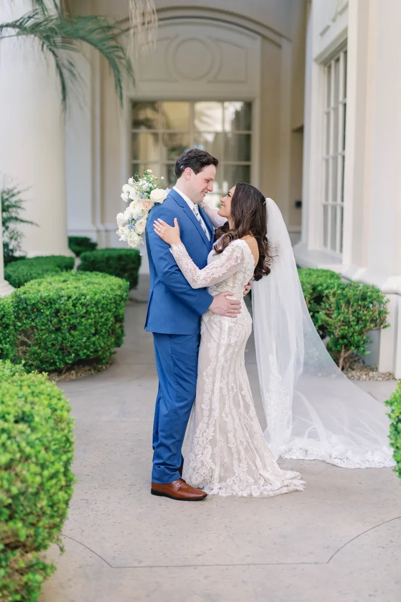 Bride and groom holding each other with her veil sweeping out behind her