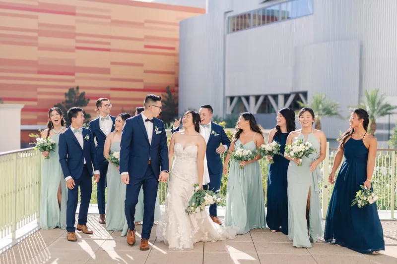 Wedding party gathered along the terrace railing, everyone laughing at once