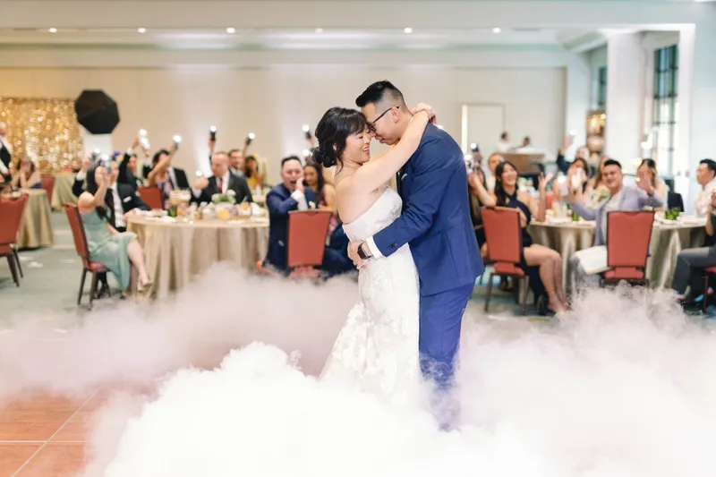 First dance with low fog rolling across the ballroom floor and guests watching from their tables