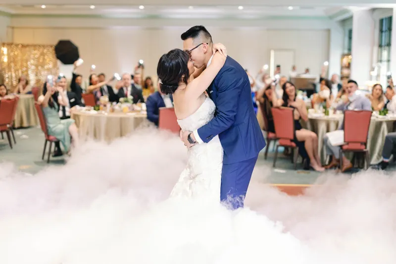 Bride and groom kissing in the middle of the fog while the tables around them look on