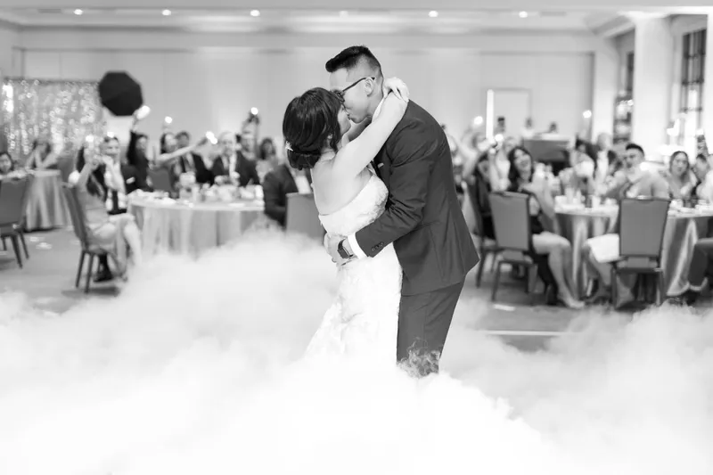Black and white frame of the groom dipping the bride at the end of the first dance
