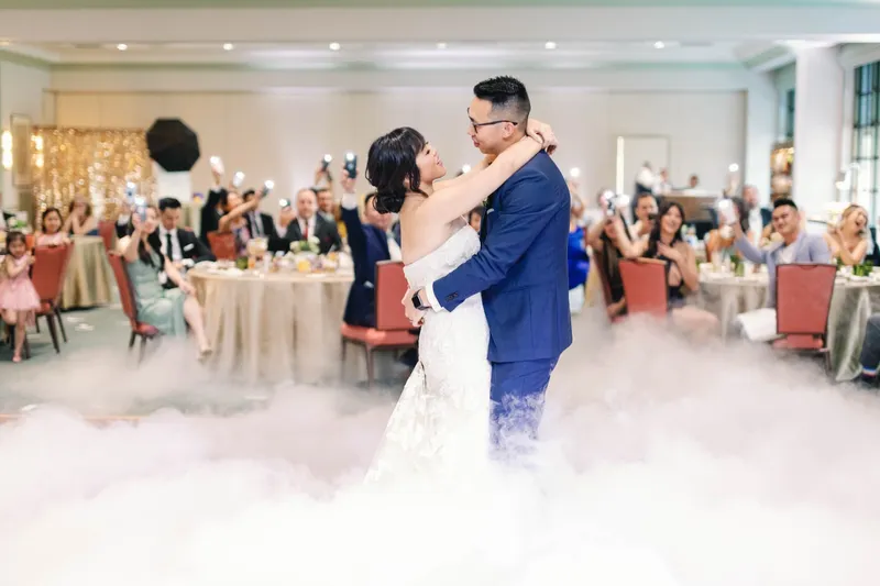 Wide view of the first dance with the whole room up and cheering around them