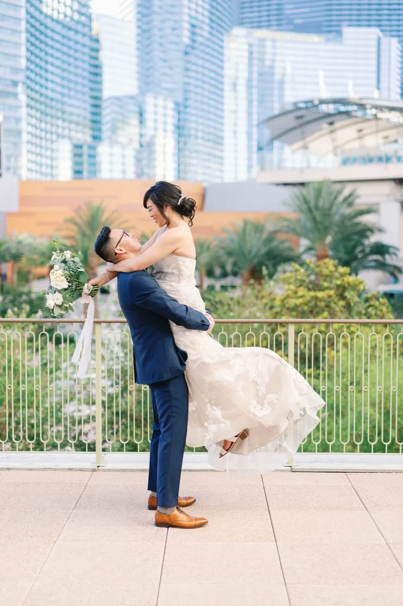 Groom lifting the bride off her feet on the terrace with the skyline behind them