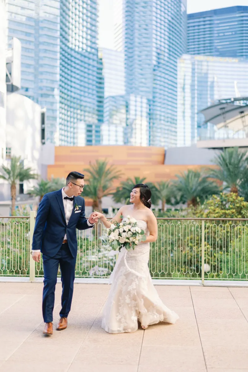 Bride and groom walking and laughing on the terrace with the Strip towers rising behind them