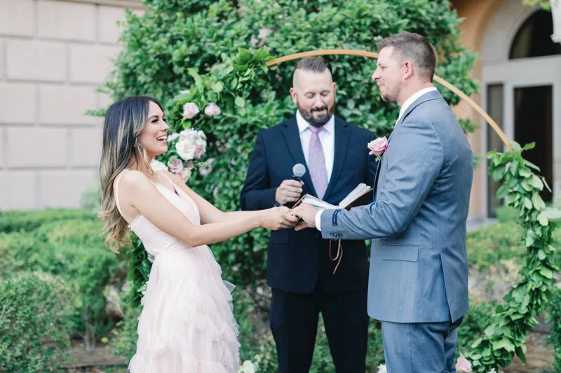 Couple holding hands through their vows while the officiant holds the microphone between them