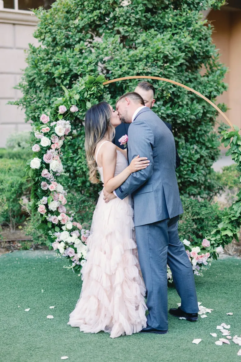First kiss under the hoop arch wrapped in ivy and blush roses