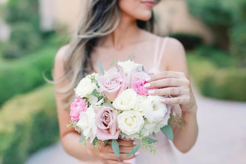 Close view of the bride's hands around a bouquet of pink and cream roses