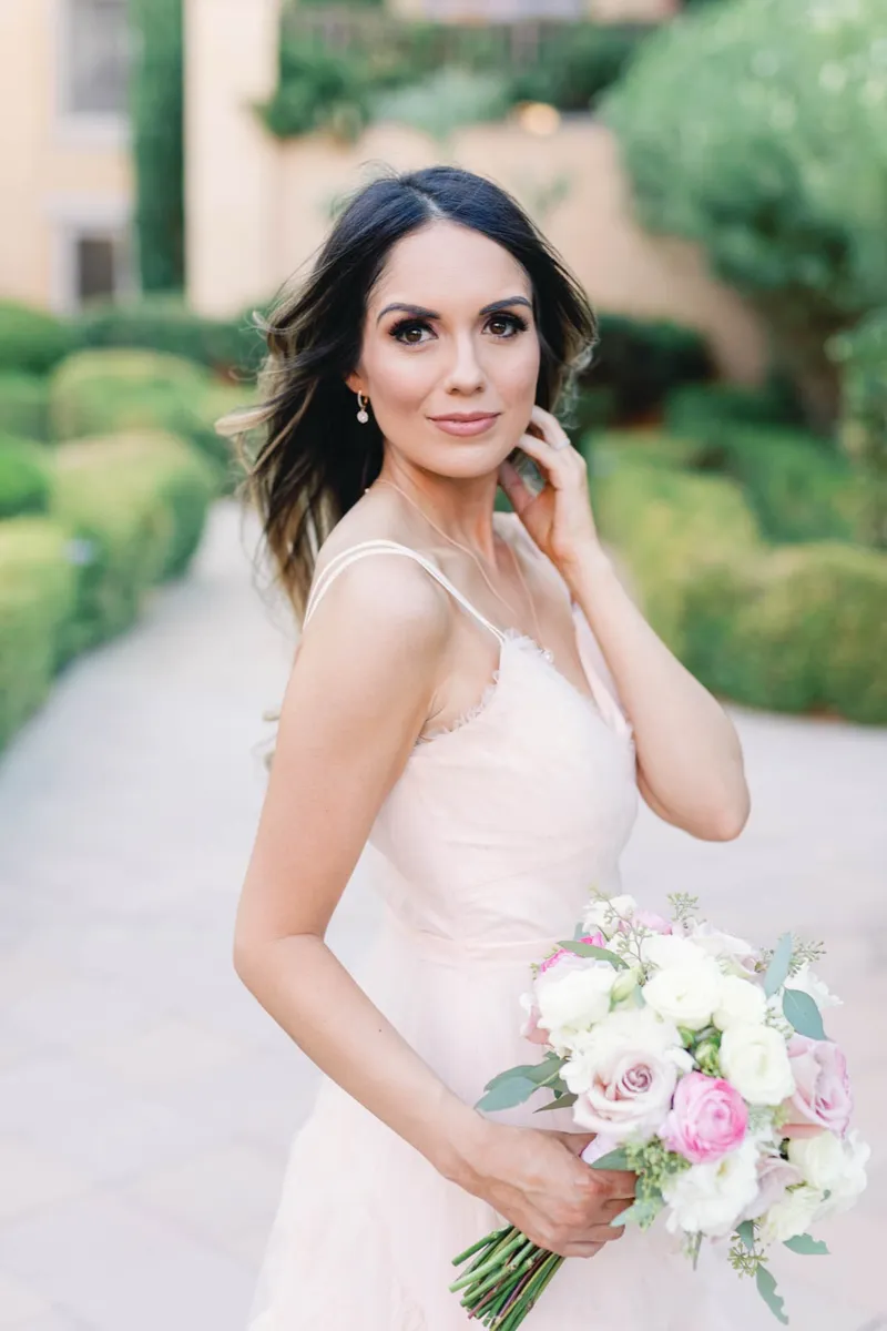 Bridal portrait with her hand at her cheek and the garden path falling away behind her