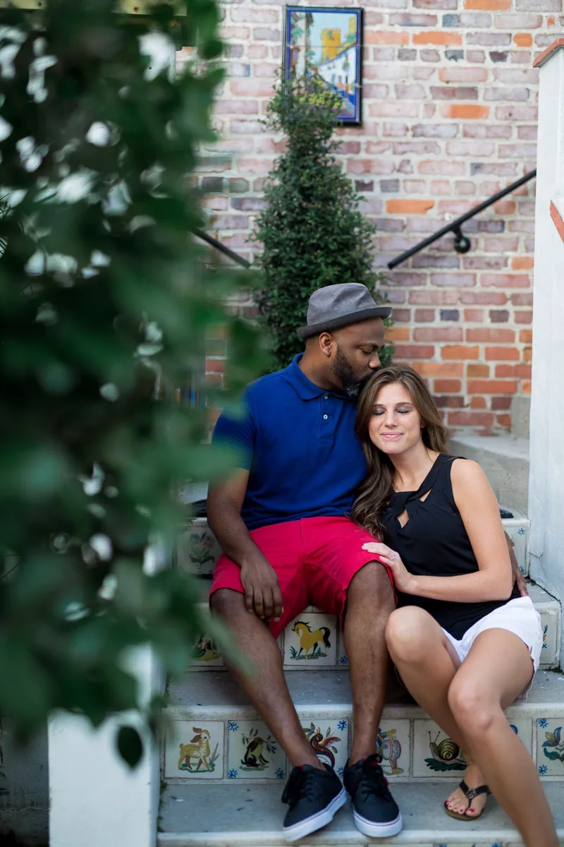An engaged couple sitting close together on tiled brick steps