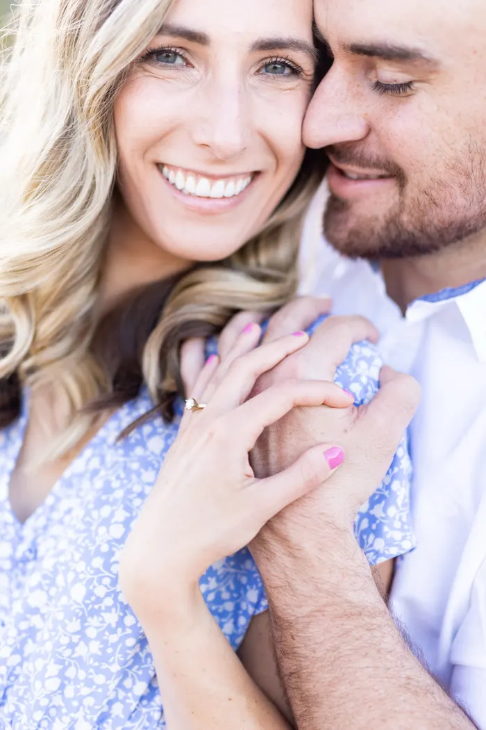 Close up of a newly engaged couple smiling with her ring showing