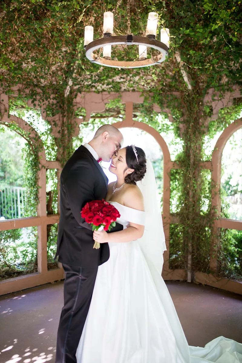 Bride and groom resting their foreheads together inside the ivy covered gazebo