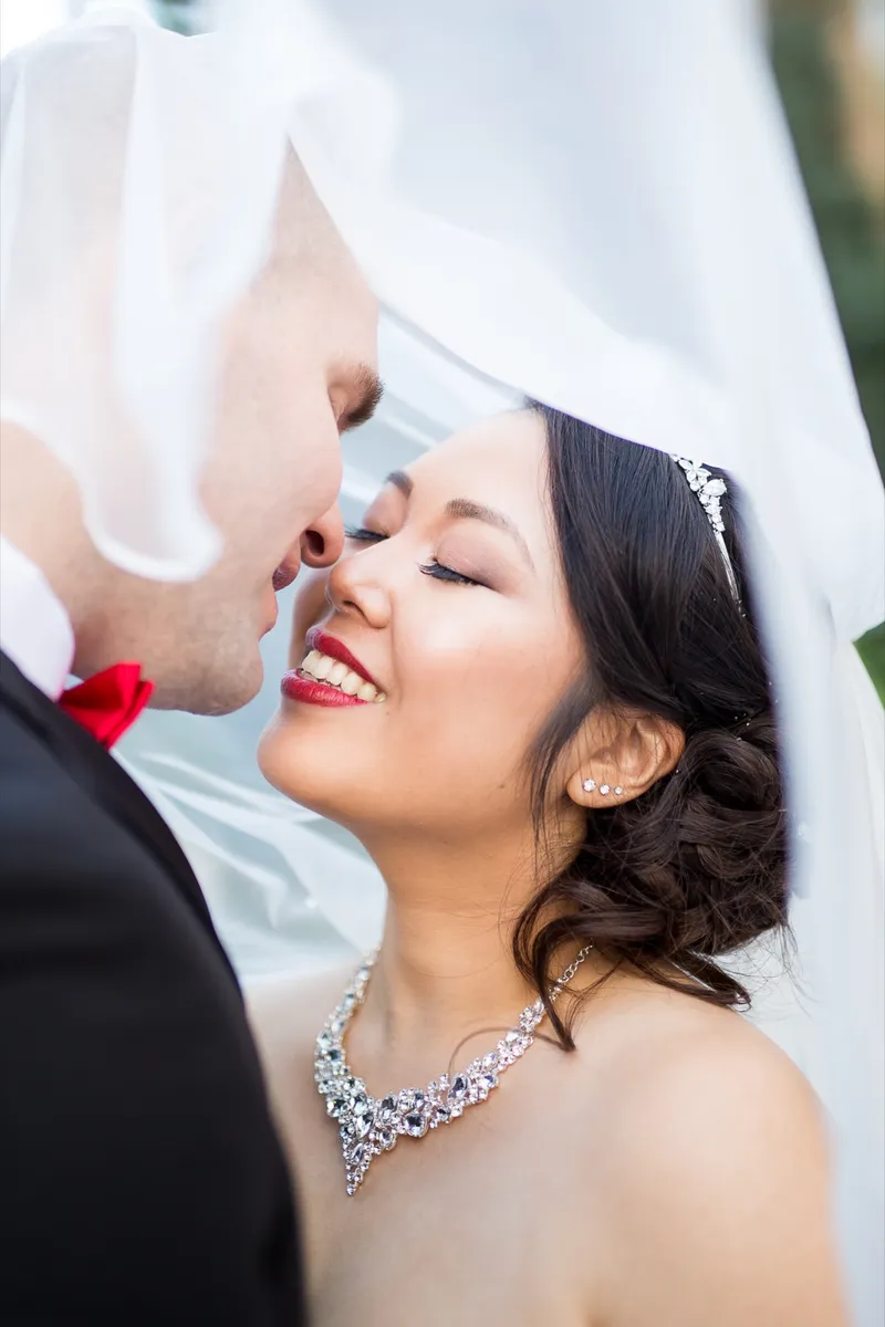 Bride and groom about to kiss under the lifted veil in a tight close crop