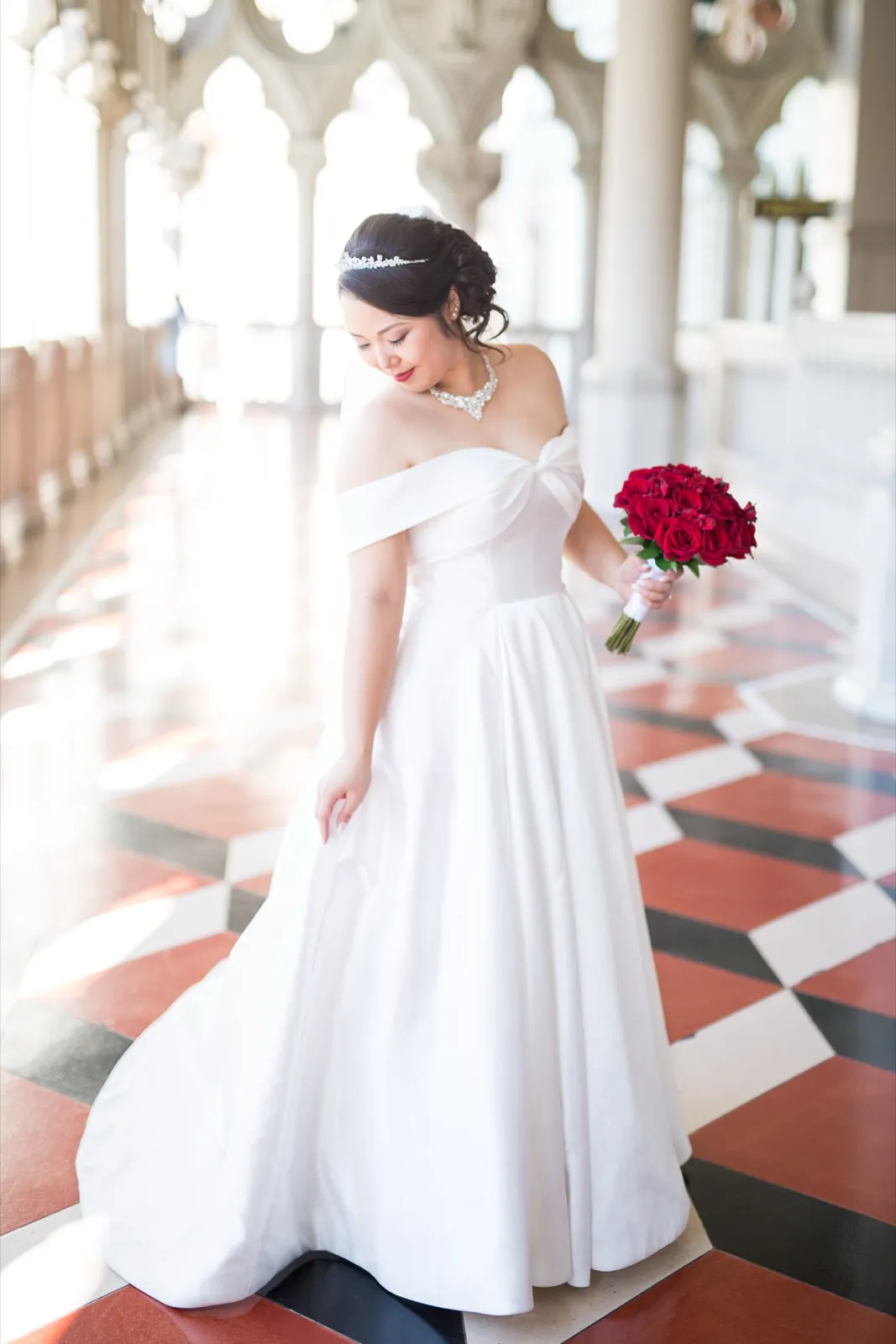 Bride mid step across the red and white checkered marble, her satin ball gown skirt swinging out