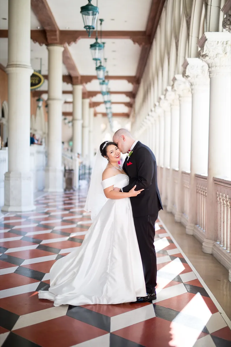 Full length portrait of the couple on the diamond patterned marble with sunlight falling in patches around them
