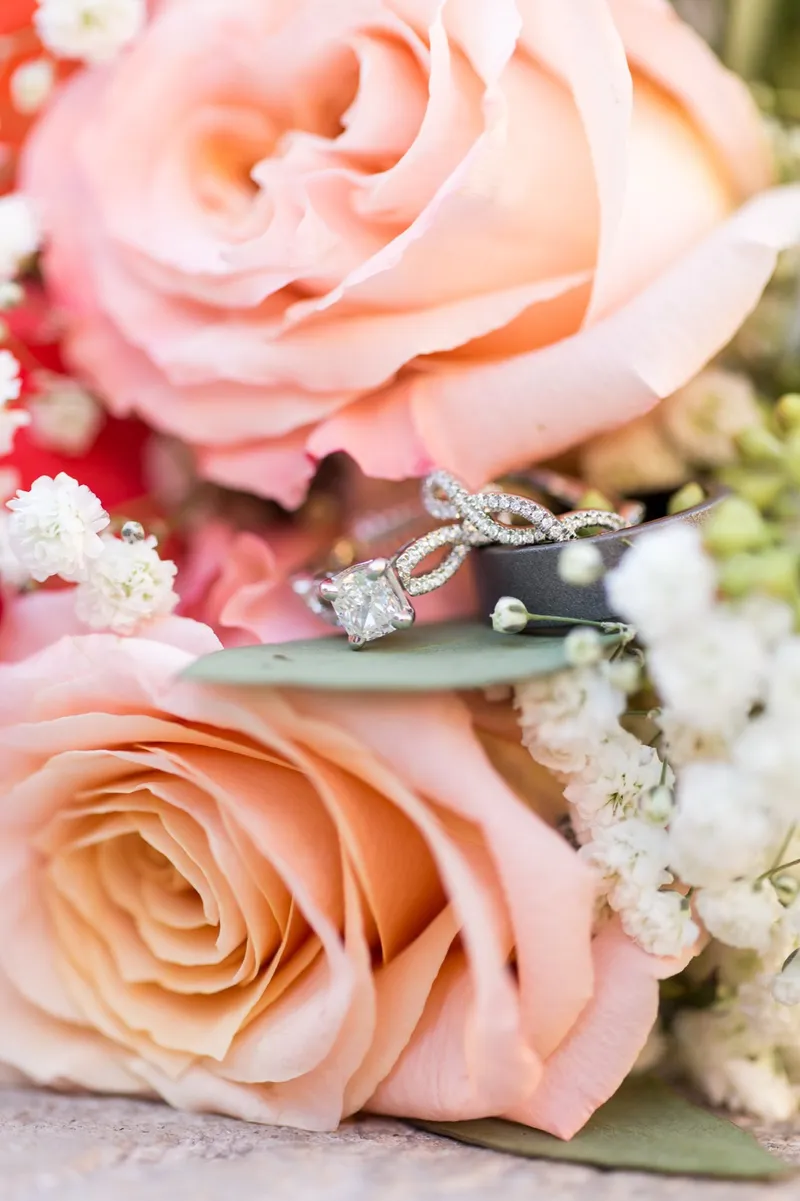 Engagement ring balanced on a leaf between two open peach roses