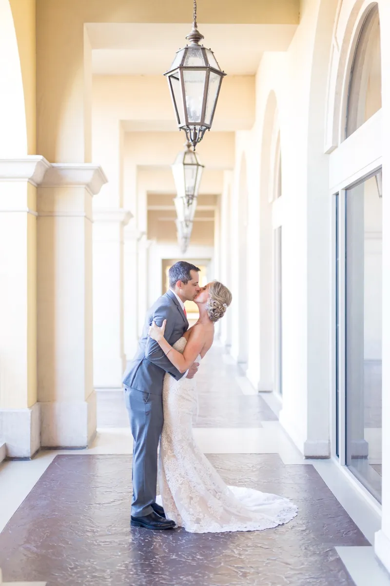 Couple kissing in the long covered walkway with lanterns hanging between the arches