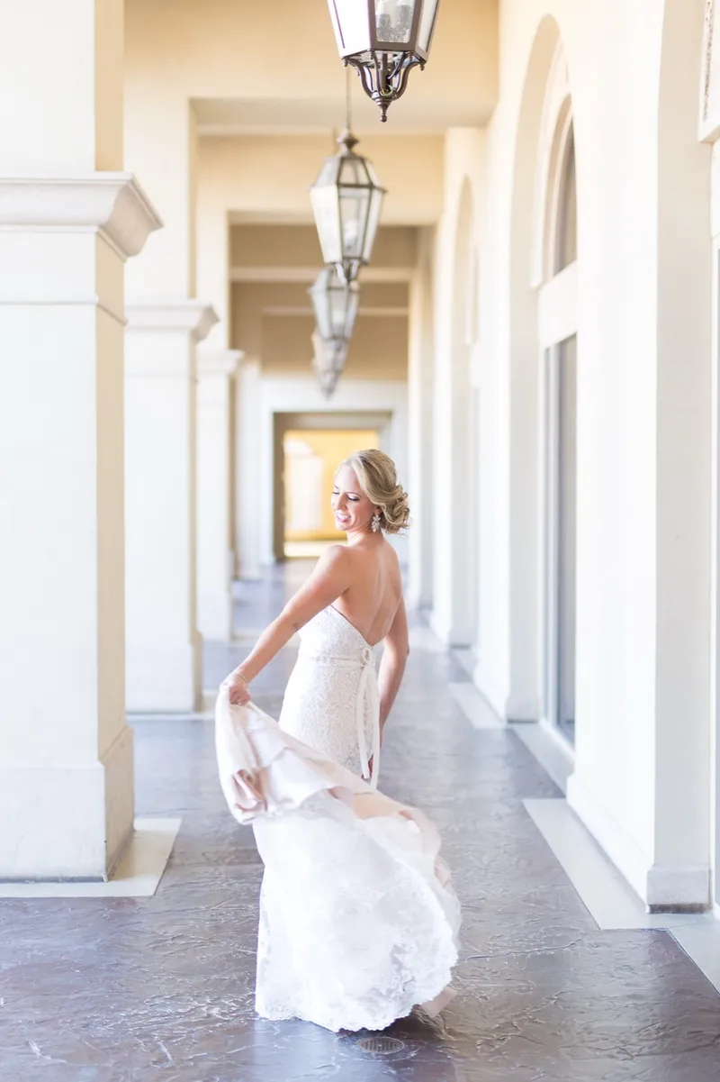 Bride swinging the skirt of her lace gown in the walkway with her back to the camera