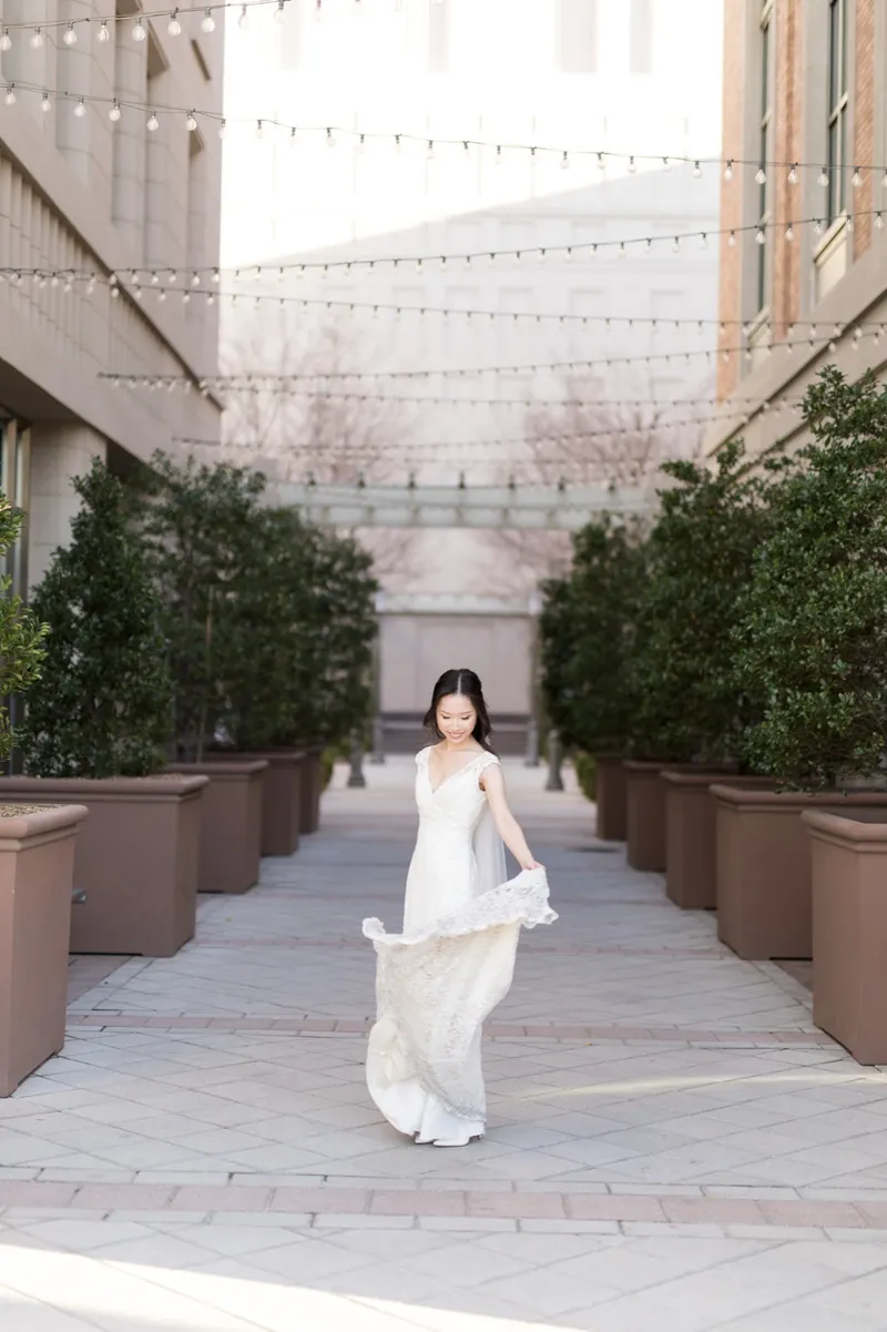 Bride swinging the skirt of her lace gown out in a circle on the empty walkway