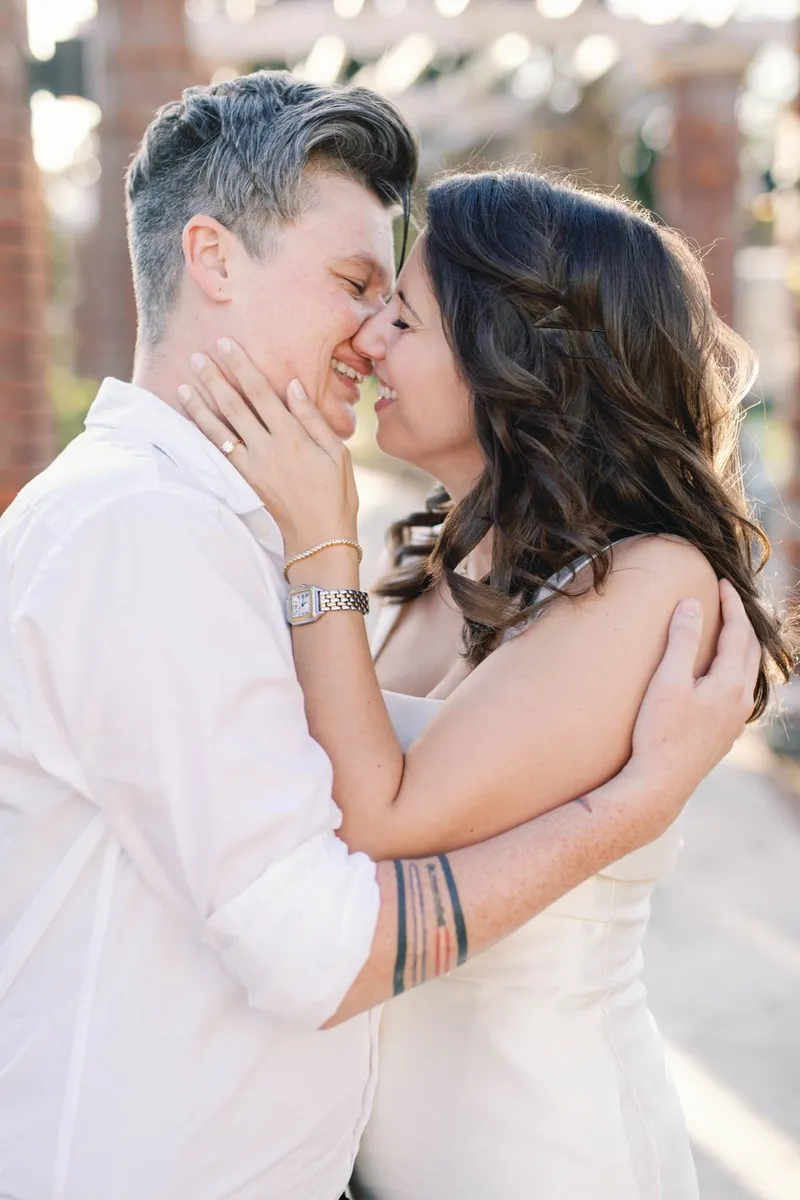Two brides nose to nose and smiling on their wedding day