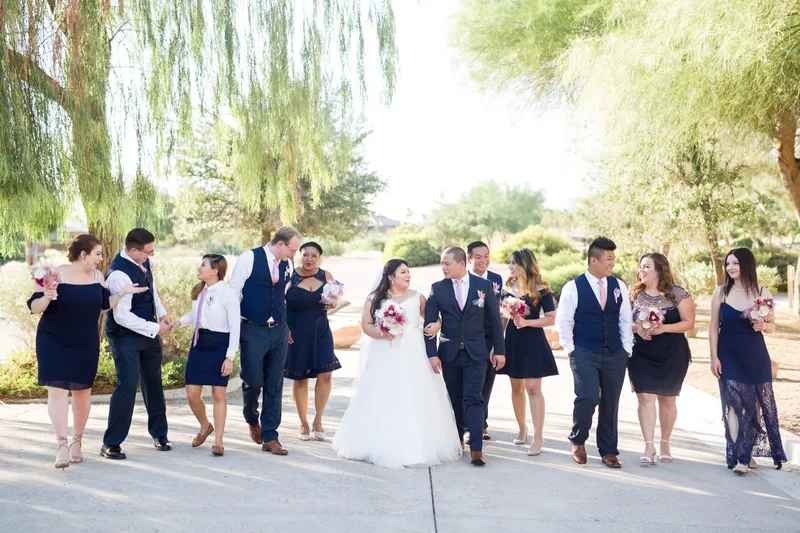 Whole wedding party walking the path together under the trees