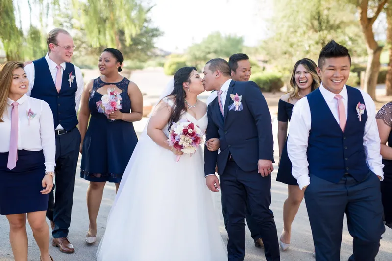 Couple stopping to kiss in the middle of their wedding party as everyone walks