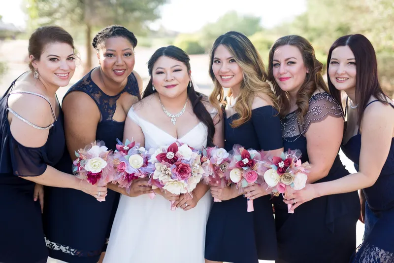 Bride with five bridesmaids in navy dresses holding pink and white bouquets on the path