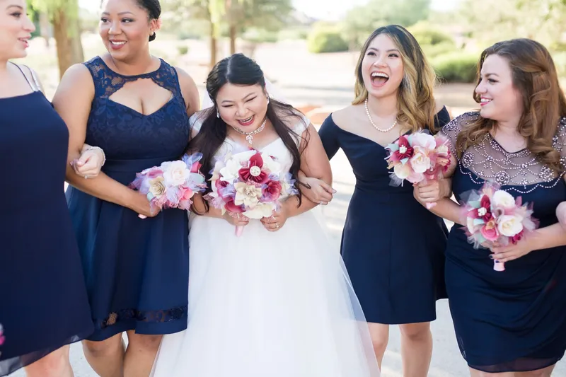 Bridesmaids laughing with the bride, all of them holding their bouquets up