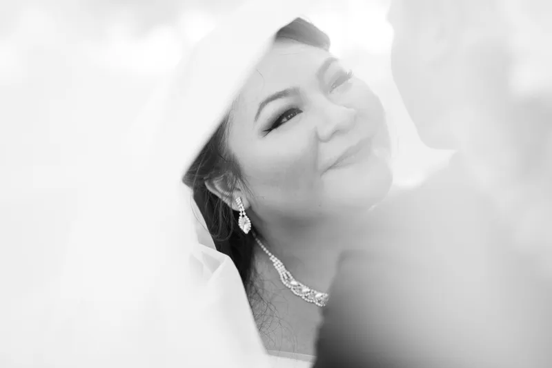 Black and white portrait of the bride smiling under her veil