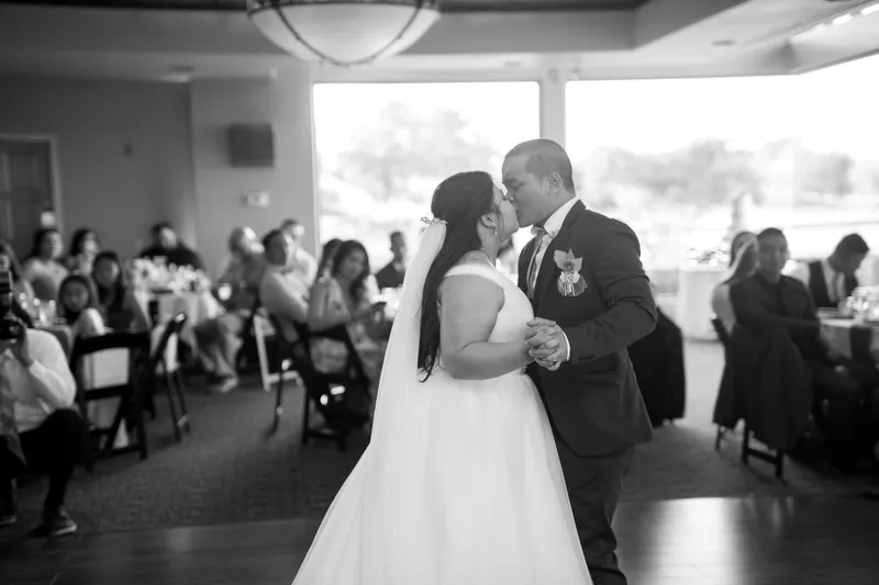 Black and white of the first dance with guests at the tables watching behind them