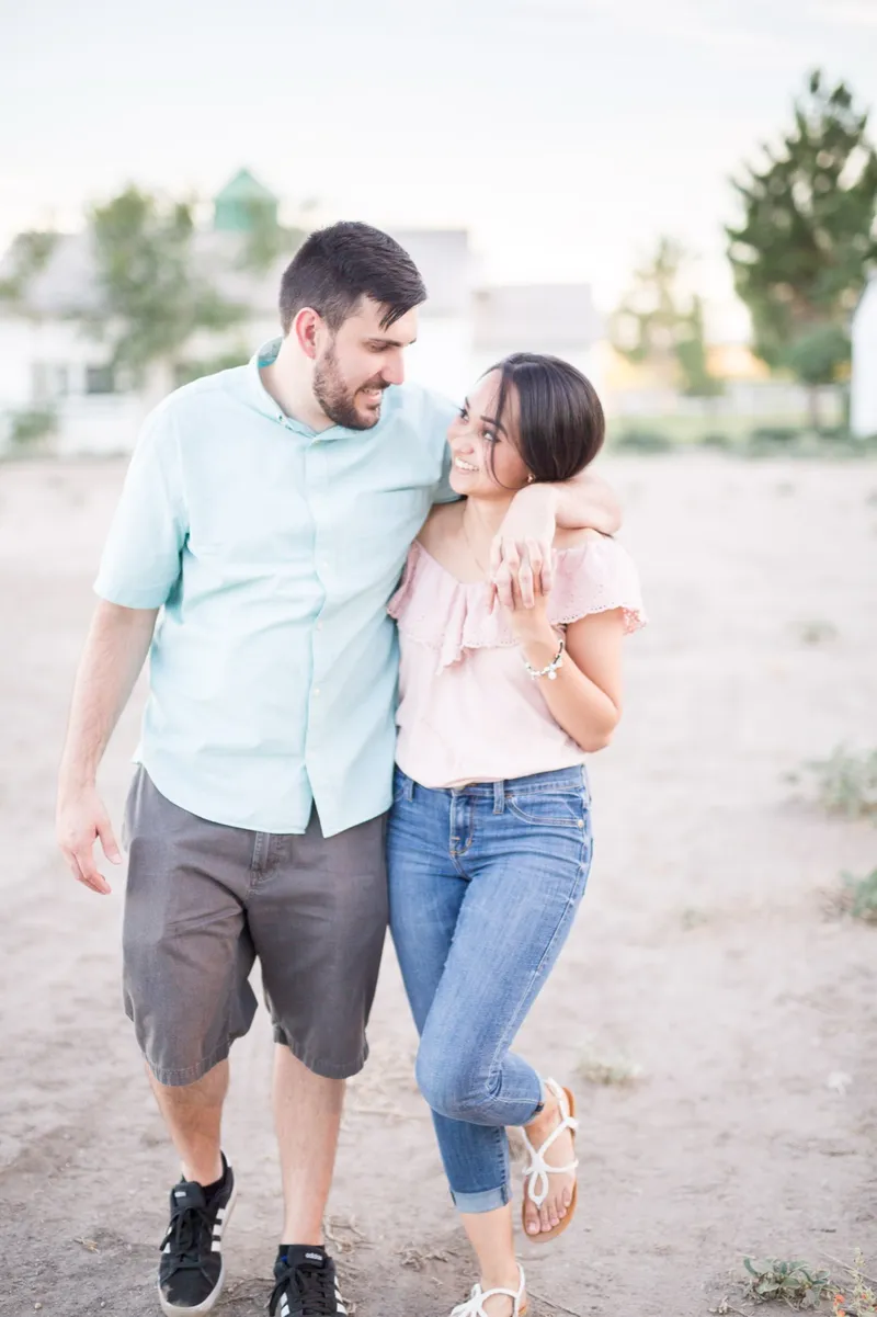 Couple walking a sandy path arm in arm, her leaning into his shoulder and laughing